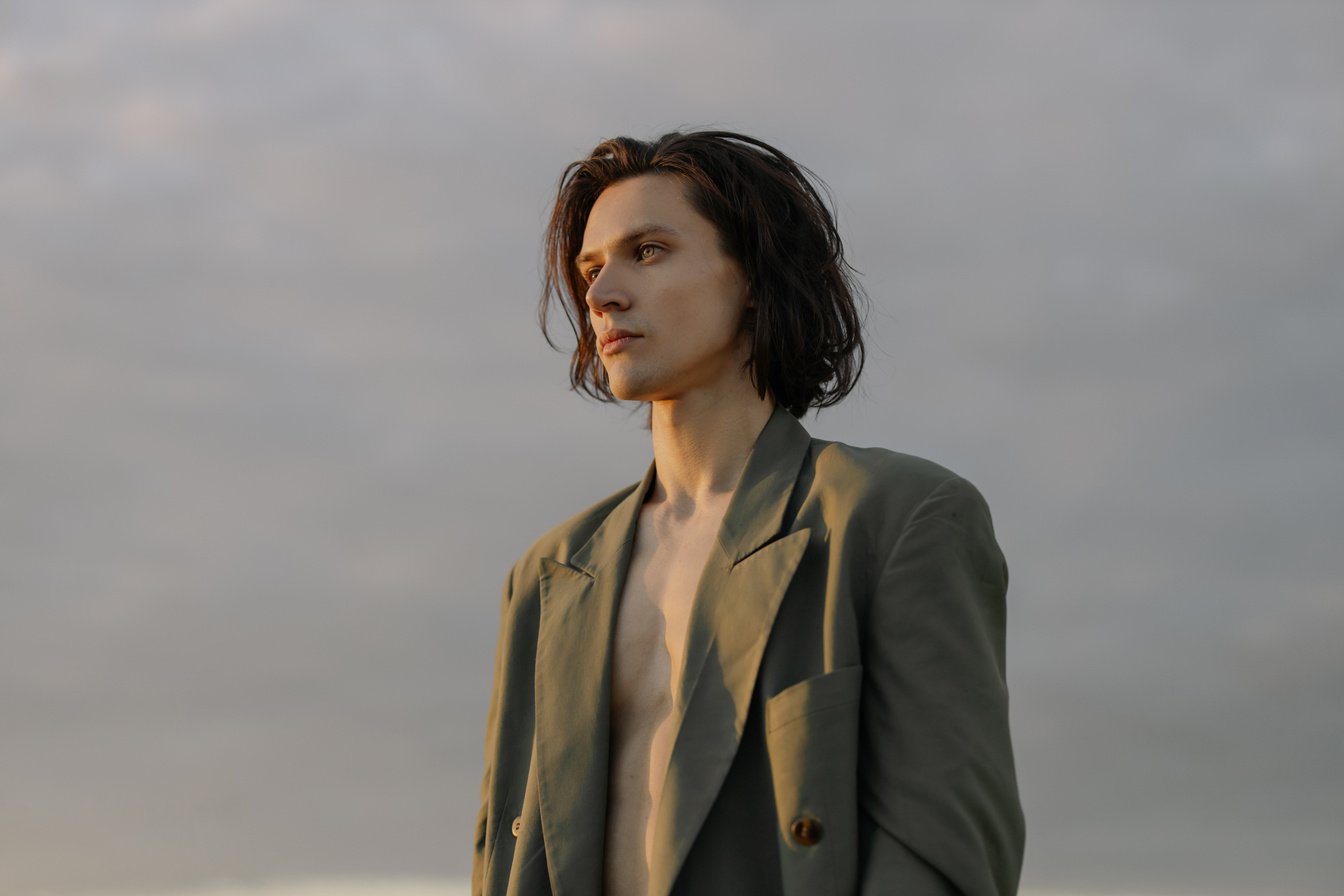 Woman in Brown Coat Standing Under White Clouds